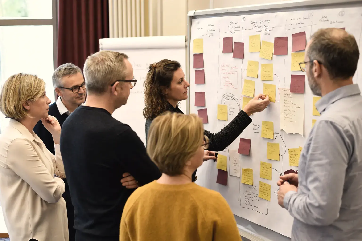 Eine Workshopgruppe arbeitet mit beschrifteten, aber nicht lesbaren Karten und Arbeitsflächen.
